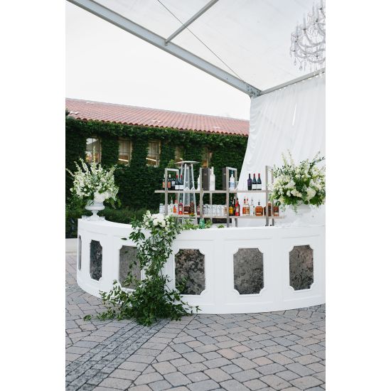 White curved Colonial Rattan event rental bar with silver stainless-steel insert panel for luxury event cocktail stations