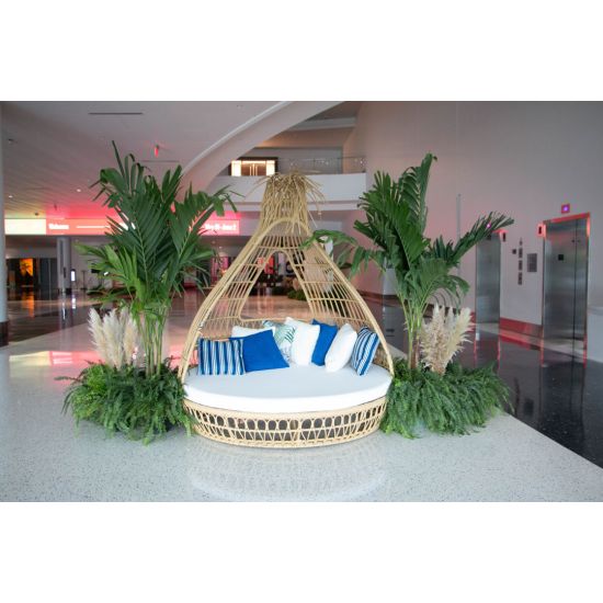 Bohemian wicker bed with teardrop canopy frame and cream cushion, statement lounge bed rental for boho weddings and outdoor events.