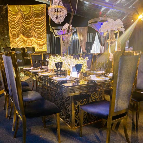 Gold Art Deco dining table 48″ × 96″ with rectangular mirrored top and bold geometric base, perfect for luxury event dining and upscale receptions
