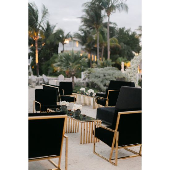 Black velvet lounge armchair with polished gold metal frame and open square base, modern luxury seating for upscale event lounges.
