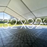 Black Duratrack subfloor under tent with 32x32 size overlay text, modular 4x4 panels used as heavy-duty outdoor event floor base.