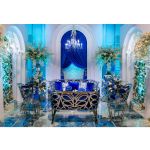 Silver reflective Butterfly Reflection armchair with circular cutout backrest and royal blue cushioned seat, modern event lounge chair rental
