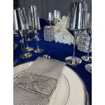 Geometric napkin holder with gold metal open-frame cube design holding a folded white cloth napkin, modern accent for event table settings