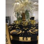Geometric napkin holder with gold metal open-frame cube design holding a folded white cloth napkin, modern accent for event table settings
