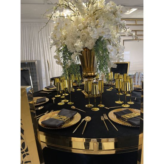 Geometric napkin holder with gold metal open-frame cube design holding a folded white cloth napkin, modern accent for event table settings