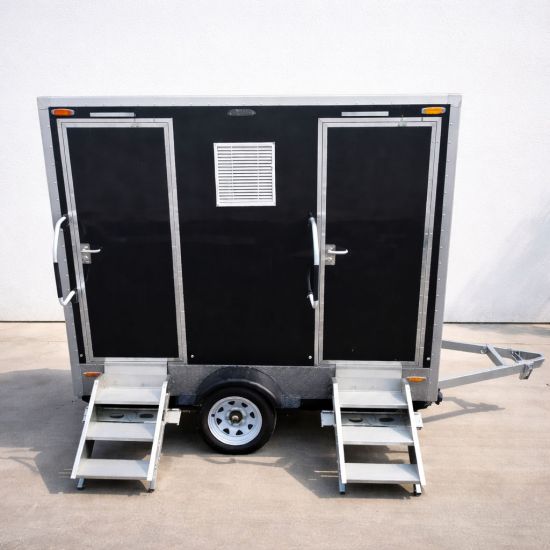 Luxury Portable RestroomBlack portable restroom trailer with dual doors, aluminum steps, diamond plate trim and tow hitch parked outdoors beside a swimming pool