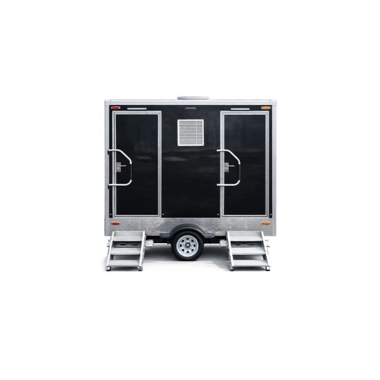 Luxury Portable RestroomBlack portable restroom trailer with dual doors, aluminum steps, diamond plate trim and tow hitch parked outdoors beside a swimming pool