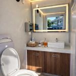 Luxury Portable RestroomBlack portable restroom trailer with dual doors, aluminum steps, diamond plate trim and tow hitch parked outdoors beside a swimming pool