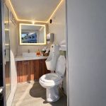 Luxury Portable RestroomBlack portable restroom trailer with dual doors, aluminum steps, diamond plate trim and tow hitch parked outdoors beside a swimming pool