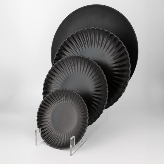 Black petal-rim onyx dessert plate with radiating ridges and a smooth center, small round plate on a white background