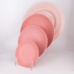 Soft pink petal-rim dinner plate with deep radiating ridges and a smooth center, large round plate on a white background