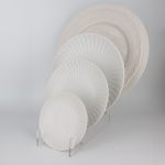 White petal-rim dessert plate with radiating ridges and a smooth center, small round plate on a white background