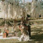Metal wire tree centerpiece with wide canopy draped in cascading white hanging florals, statement decor for weddings and event backdrops.