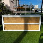 White cane-woven front event bar rental unit with smooth white frame and countertop for modern lounge-style weddings and cocktail receptions