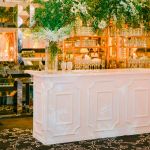 White Colonial Rattan event bar rental unit with rattan-weave front panel for stylish wedding and cocktail receptions