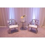 Silver reflective Butterfly Reflection armchair with circular cutout backrest and white cushioned seat, modern event lounge chair rental