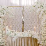 Gold candle wall backdrop with diamond lattice grid and freestanding base, elegant wedding decor display for candles and event styling.
