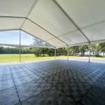 Black Duratrack subfloor under tent with 32x32 size overlay text, modular 4x4 panels used as heavy-duty outdoor event floor base.