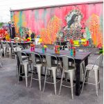 Orange metal bar stool with backrest and foot-rail, urban industrial event seating for bar height tables
