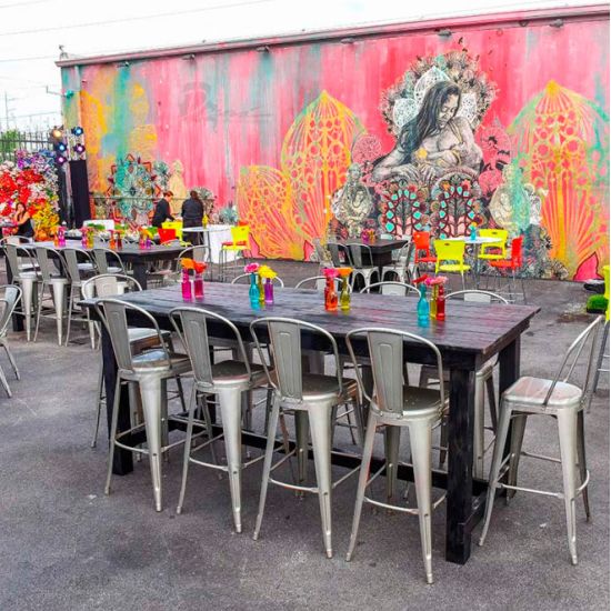 Orange metal bar stool with backrest and foot-rail, urban industrial event seating for bar height tables