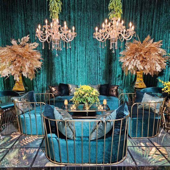 Yellow velvet accent loveseat with gold metal bar frame and two black pillows, modern art deco lounge seating for luxury events.